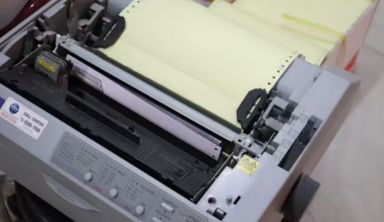 Industrial dot matrix printer using continuous pin-feed paper and impact printing, ideal for multi-part forms and business document management.